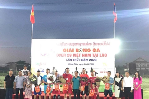Đại diện Đại sứ quán Việt Nam tại Lào cùng các đại biểu tặng hoa và cờ lưu niệm cho tổ trọng tài và 7 đội tham dự giải. (Ảnh: Thu Phương/TTXVN)