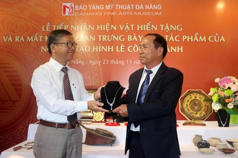 Giám đốc Bảo tàng Mỹ Thuật Đà Nẵng Hà Thanh Vân (trái) nhận các hiện vật do người dân hiến tặng tại buổi lễ. (Ảnh: Trần Lê Lâm/TTXVN)
