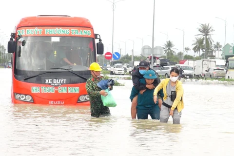 Lực lượng quân đội hỗ trợ cứu nạn người dân bị mắc kẹt trong xe buýt đến nơi an toàn. (Ảnh: Phan Sáu/Vietnam+)