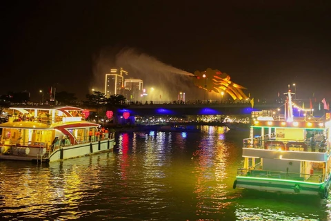 Các du thuyền đưa du khách ngắm cầu Rồng phun nước trong tour du lịch miễn phí thưởng ngoạn ngắm sông Hàn về đêm. (Ảnh: Trần Lê Lâm/TTXVN)