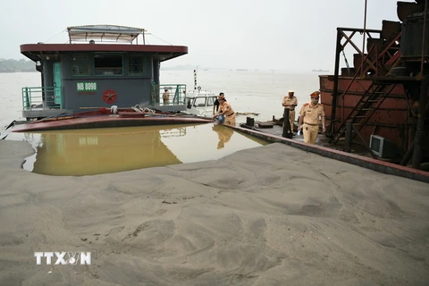 Cán bộ Cục Cảnh sát giao thông tiến hành kiểm tra người và phương tiện trong một vụ khai thác cát trái phép trên sông Hồng. (Ảnh: TTXVN phát)