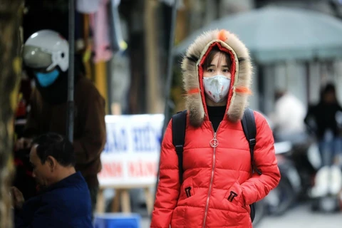 Người dân ra đường đều mặc áo ấm kín mít, đeo khẩu trang để chống lại cơn gió lạnh. (Ảnh: Thành Đạt/TTXVN)