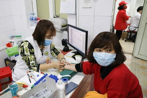 Lấy mẫu máu xét nghiệm cho tình nguyện viên đăng ký hiến máu. (Ảnh: TTXVN)