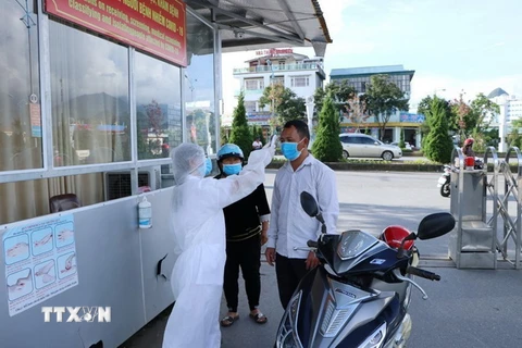 Cán bộ nhân viên y tế của Bệnh viện Đa khoa tỉnh Lai Châu kiểm soát đo thân nhiệt cho người dân trước khi vào khám bệnh. (Ảnh: Quý Trung/TTXVN)