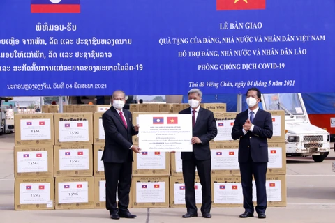 Thứ trưởng Bộ Y tế Nguyễn Trường Sơn đang trao tượng trưng 2 triệu khẩu trang y tế và 200 máy thở và các vật tư y tế là quà tặng của Đảng, Nhà nước và nhân dân Việt Nam dành cho Đảng, Nhà nước và nhân dân Lào trong công tác phòng chống COVID-19. (Ảnh: Phạ