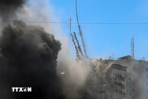 Tòa tháp Jala, nơi đặt văn phòng một số hãng truyền thông quốc tế, bị đổ sập do trúng không kích của Israel tại Dải Gaza, ngày 15/5. (Ảnh: AFP/TTXVN)