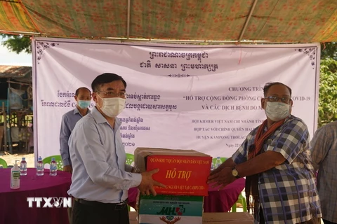 Công sứ sứ quán Việt Nam tại Campuchia Lại Xuân Chiến (trái) trao tặng vật tư y tế chống dịch cho đại diện chính quyền hai xã Saeb và Ta Ches, huyện Kampong Trolach. (Ảnh: Trần Long/TTXVN)