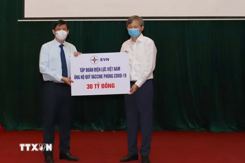 Tổng Giám đốc EVN Trần Đình Nhân trao tượng trưng tiền ủng hộ Quỹ Vaccine phòng COVID-19 cho Bộ trưởng Bộ Y tế Nguyễn Thanh Long. (Ảnh: TTXVN phát)