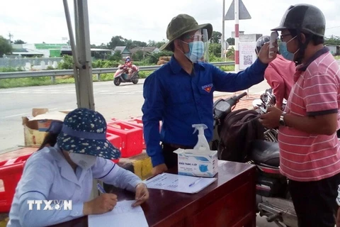 Đoàn viên thanh niên tham gia đo thân nhiệt tại chốt kiểm dịch ở cầu Mỹ Lợi, thị xã Gò Công, Tiền Giang. (Ảnh: Hữu Chí/TTXVN)