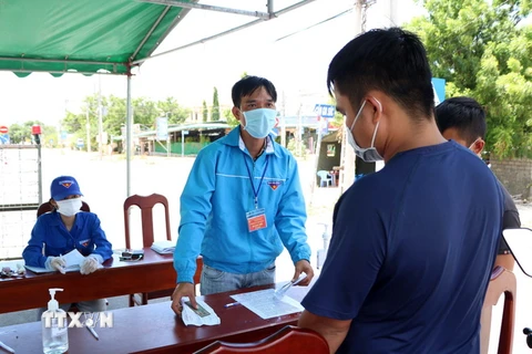 Lực lượng trực chốt kiểm soát dịch bệnh huyện Ninh Hải kiểm tra giấy xác nhận và đo thân nhiệt người dân đi, về địa phương. (Ảnh: Công Thử/TTXVN)