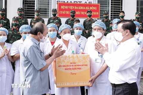 Chủ tịch nước Nguyễn Xuân Phúc tặng quà các nhân viên y tế làm việc cơ sở thu dung, điều trị bệnh nhân COVD-19 của Bệnh viện Đa khoa Hà Đông. (Ảnh: Thống Nhất/TTXVN)