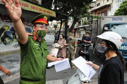 Kiểm tra giấy đi đường của người dân tại chốt kiểm soát phường Hàng Buồm. (Ảnh: TTXVN)