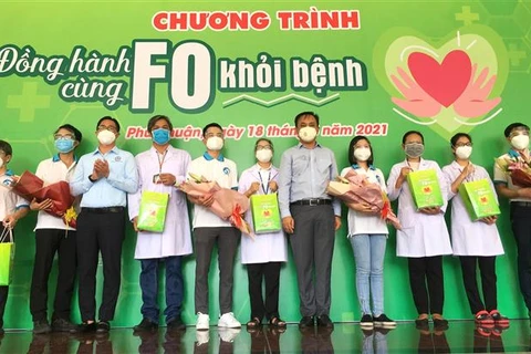 Hội Thầy thuốc trẻ Thành phố Hồ Chí Minh cùng lãnh đạo quận Phú Nhuận tặng hoa và quà cho đội hình Đồng hành cùng F0 khỏi bệnh. (Ảnh: Thanh Vũ/TTXVN)