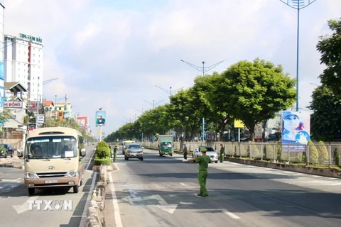 Lực lượng chức năng kiểm soát chặt các phương tiện lưu thông trên đường Trường Chinh, đoạn qua quận 12. (Ảnh: Tiến Lực/TTXVN)