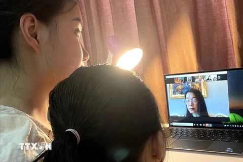 Phụ huynh cùng học sinh lớp 1 (năm học 2021-2022) của trường Tiểu học Thăng Long, quận Hoàn Kiếm trao đổi cùng giáo viên chủ nhiệm lớp để làm quen với việc học trực tuyến của trẻ. (Ảnh: TTXVN phát)