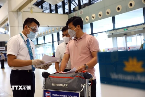 Nhân viên của Vietnam Airlines kiểm tra giấy tờ của hành khách trước khi vào làm thủ tục. (Ảnh: Huy Hùng/TTXVN)