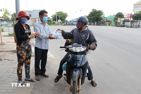 Tặng các suất cơm, nước uống miễn phí cho những người trở về quê bằng xe máy từ các tỉnh, thành phía Nam trên Quốc lộ 1A đoạn qua thành phố Phan Rang-Tháp Chàm, tỉnh Ninh Thuận. (Ảnh: Nguyễn Thành/TTXVN)
