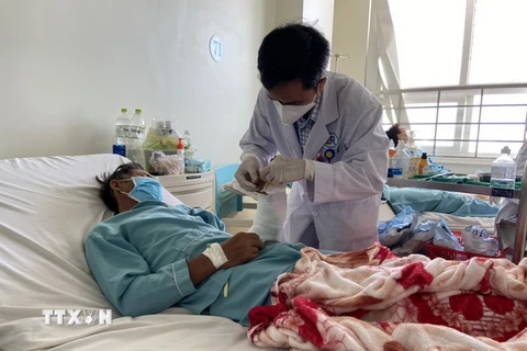 Bác sỹ Phan Văn Tú, Khoa Ngoại chấn thương Chỉnh hình khám cho bệnh nhân Đinh Huy Hoàng sau khi phẫu thuật. (Ảnh: TTXVN phát)
