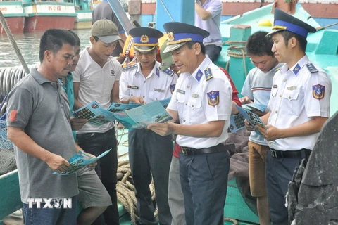 Lực lượng Vùng Cảnh sát biển trực tiếp phát tờ rơi tuyên truyền các quy định tới ngư dân. (Ảnh: TTXVN phát)