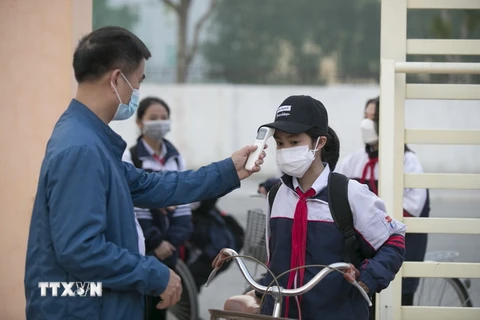 Đo thân nhiệt cho học sinh trước khi vào lớp học ở trường THCS Quán Bàu, thành phố Vinh. (Ảnh: TTXVN)
