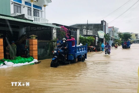 Lực lượng chức năng huyện Tuy Phước, tỉnh Bình Định, vận chuyển cát giúp người dân đắp bờ nước lũ tràn vào nhà. (Ảnh: TTXVN phát)