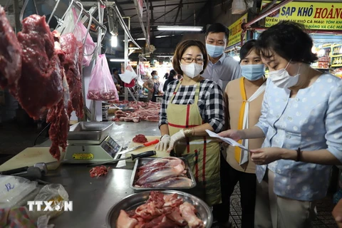 Cán bộ Ban quản lý kiểm tra chứng từ chứng minh nguồn gốc thực phẩm của tiểu thương tại chợ Phạm Văn Hai, Thành phố Hồ Chí Minh. (Ảnh: Hồng Giang /TTXVN)