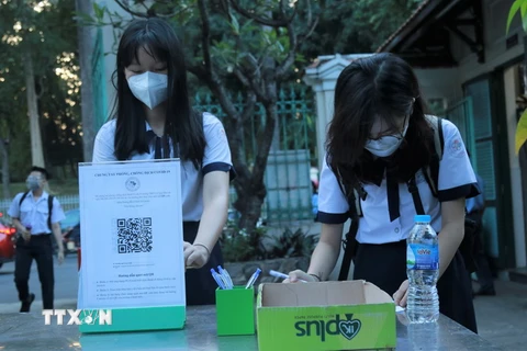 Học sinh Trường THPT Lê Quý Đôn (quận 3) khai báo y tế ở khu vực ngoài cổng trường. (Ảnh: Thu Hoài/TTXVN)