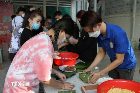 Các bạn sinh viên Lào, Trường Đại học Nha Trang gói bánh chưng theo hướng dẫn của thầy cô, bạn bè người Việt Nam. (Ảnh: Phan Sáu/TTXVN)