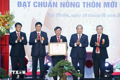 Chủ tịch nước Nguyễn Xuân Phúc trao Bằng chứng nhận huyện đạt chuẩn nông thôn mới cho lãnh đạo huyện Tuy Phước. (Ảnh: Thống Nhất/TTXVN)