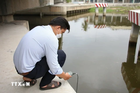 Cán bộ kỹ thuật Công ty THHH Một thành viên Khai thác công trình thủy lợi Bến Tre kiểm tra độ mặn khu vực cống Trung Nhuận, huyện Giồng Trôm, tỉnh Bến Tre. (Ảnh: Công Trí/TTXVN)