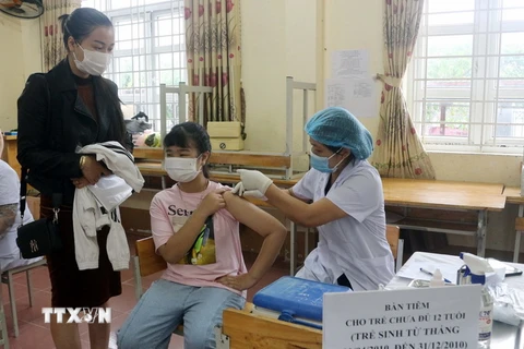 Trẻ được tiêm tại điểm tiêm trường THCS Lương Khánh Thiện, thành phố Phủ Lý, dưới sự theo dõi của phụ huynh và nhân viên y tế. (Ảnh: Đại Nghĩa/TTXVN)