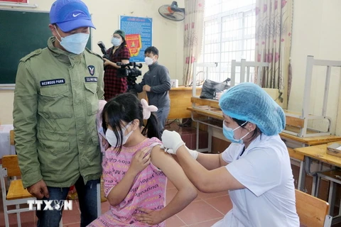 Trẻ em được tiêm tại điểm tiêm trường THCS Lương Khánh Thiện, thành phố Phủ Lý, dưới sự theo dõi của phụ huynh và nhân viên y tế. (Ảnh: Đại Nghĩa/TTXVN)