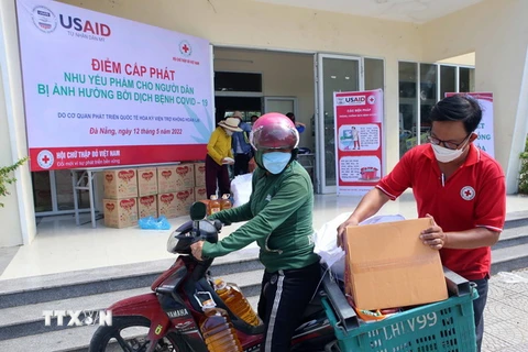 Nhân viên Hội Chữ thập đỏ hỗ trợ người dân vận chuyển nhu yếu phẩm về nhà. (Ảnh: Trần Lê Lâm/TTXVN) 