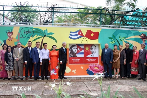 Các đại biểu chụp hình lưu niệm bên bức tranh vẽ cổ động về tình hữu nghị nhân dân Việt Nam-Cuba. (Ảnh: Tiến Lực/TTXVN)