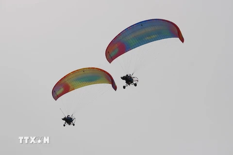 Các phi công bay biểu biễn kết hợp với bay dù lượn có động cơ tại Công viên Thanh Niên với độ cao từ 50m đến 100m. (Ảnh: Phan Sáu/TTXVN)