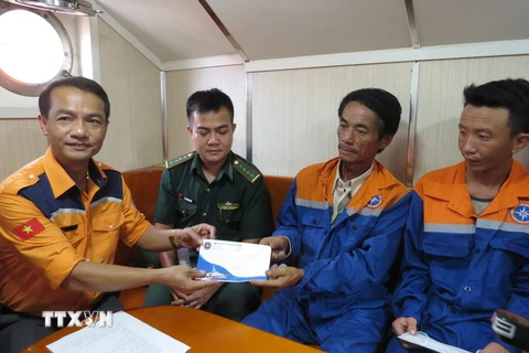 Đại diện Trung tâm Phối hợp tìm kiếm, cứu nạn hàng hải Việt Nam trao quà hỗ trợ cho các thuyền viên tàu cá Bình Định sau khi được cứu nạn trên biển. (Ảnh: Phan Sáu/TTXVN)