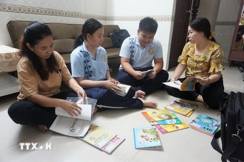 Hai anh em Võ Quang Duy Anh và Võ Thùy Lâm, ở 1uận 10, TP.HCM, cùng mẹ và mẹ đỡ đầu chuẩn bị sách vở cho năm học mới. (Ảnh: Thu Hoài/TTXVN)
