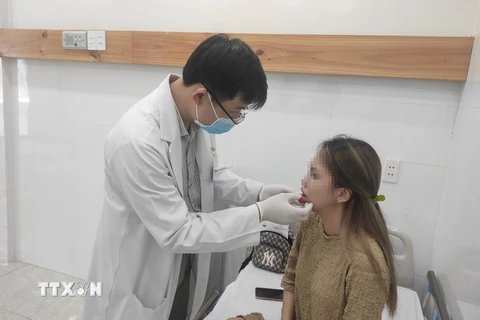 Bác sỹ Bệnh viện Da liễu Thành phố Hồ Chí Minh thăm khám cho một bệnh nhân biến chứng sau khi tiêm chất làm đầy tại spa. (Ảnh: TTXVN phát)