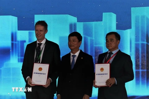 Chủ tịch UBND tỉnh Bình Dương Võ Văn Minh trao Giấy chứng nhận đầu tư cho đại diện Tập đoàn LEGO và chủ đầu tư Khu công nghiệp VSIP3. (Ảnh: Chí Tưởng/TTXVN)