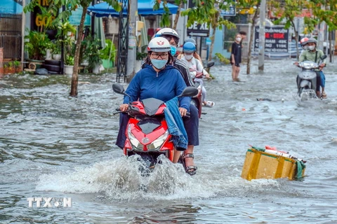 Nước ngập sâu trên tuyến đường ven hồ Búng Xáng khiến việc đi lại của người dân gặp khó khăn. (Ảnh: Thanh Liêm/TTXVN)