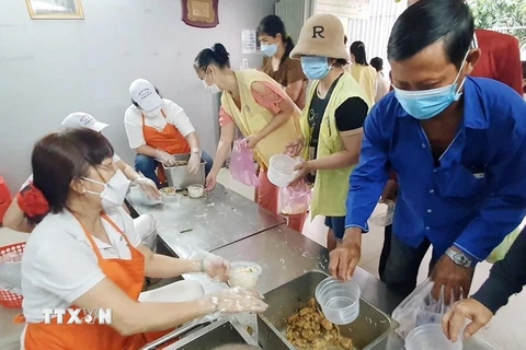 Các thành viên tại Bếp yêu thương chia từng phần cháo chay nóng hổi đến cho người dân tại Bệnh viện Chợ Rẫy. (Ảnh: Thu Hương/TTXVN)