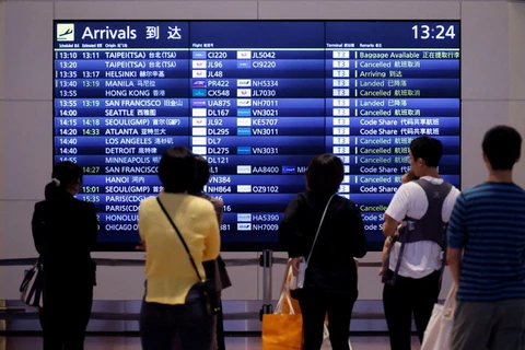 Mọi người đứng trước bảng thông tin chuyến bay tại Sân bay Quốc tế Haneda, Nhật Bản. (Nguồn: Reuters)