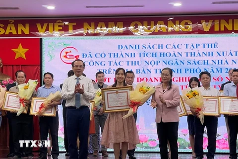 Lãnh đạo Thành ủy, UBND TPHồ Chí Minh trao tặng bằng khen cho đại diện doanh nghiệp thực hiện tốt công tác nộp ngân sách năm 2022. (Ảnh: Hứa Chung/TTXVN)