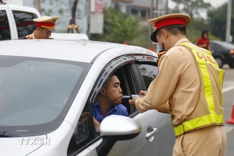 Cảnh sát giao thông kiểm tra nồng độ cồn của lái xe. (Ảnh: Nam Sương/TTXVN)