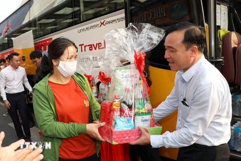 Lãnh đạo Saigon Co.op tặng quà cho người lao động trước khi khởi hành “Chuyến xe hạnh phúc” đưa người lao động về quê ăn Tết. (Ảnh: Thanh Vũ/TTXVN)