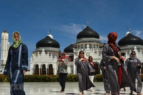 Khách du lịch nước ngoài thăm nhà thờ Hồi giáo Baiturrahman ở Banda Aceh của Indonesia. (Ảnh: AFP/TTXVN)