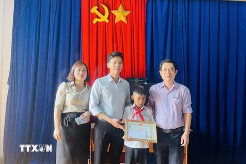 Ủy ban Nhân dân xã Kim Tân tặng Giấy khen cho em Kpă Nguyên vì đã có hành động dũng cảm cứu người bị đuối nước. (Ảnh: Quang Thái/TTXVN)