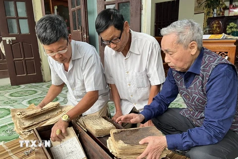 Các thành viên ban quản lý di tích Đền Quốc Tế ở xã Dị Nậu, huyện Tam Nông, tỉnh Phú Thọ, bên các cuốn sách cổ và sắc phong hiện đang được lưu giữ tại nhà dân. (Ảnh: Đào An/TTXVN)