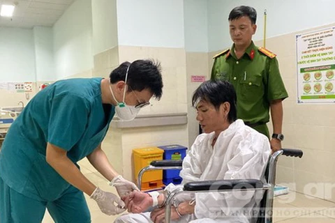 Bác sỹ chăm sóc vết thương cho đối tượng Nguyễn Đức An dưới sự giám sát, hỗ trợ của cán bộ Công an. (Nguồn: Công an Thành phố Hồ Chí Minh)