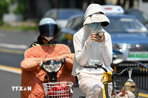 Người dân mặc áo chống nắng bảo vệ trong thời tiết nắng nóng gay gắt tại Thượng Hải, Trung Quốc. (Ảnh: AFP/TTXVN)